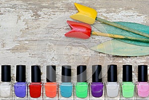 Nail polish bottles of different colors on white wooden table.