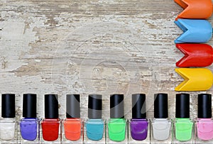 Nail polish bottles of different colors on white wooden table.