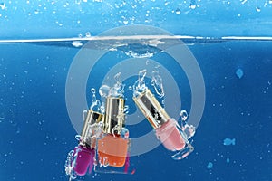 Nail polish bottles under water with trail of transparent bubbles,