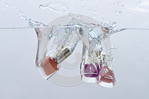 Nail polish bottles under water with trail of transparent bubbles.
