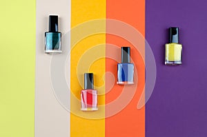 Nail polish of different colors on a colorful background top view