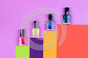 Nail polish of different colors on a colorful background top view.