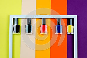 Nail polish of different colors inside a white frame top view