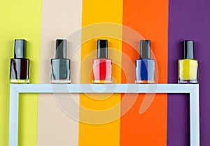 Nail polish of different colors on a white frame top view