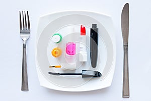 Nail polish, lipstick and mascara on a white plate with cutlery