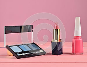 Nail polish, lipstick, powder on a pink pastel background. Minimalist trend.