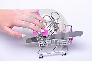 Nail polish, scissors, nail file, shopping cart with cosmetics. Online cosmetics store for women.