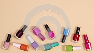 Nail polishes bottles falling on beige background. Stop motion flay lay