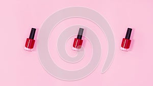 Nail polishes bottles rotate on pastel pink background. Stop motion