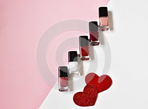 Nail polishes and hearts on white-pink background.