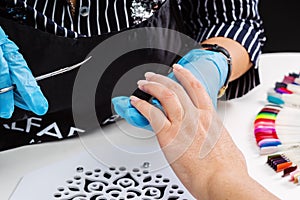 Nail salon, hands of master and client, processing nails with manicure scissors