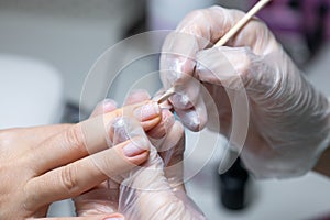 The nail service master does a manicure cleans dirt from under the nails with a wooden stick