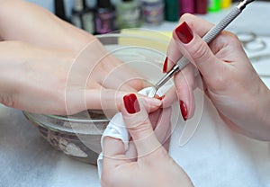 Nail technician cuts the cuticles on the hands in the beauty salon. photo