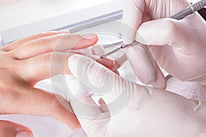 Nail technician giving customer a manicure at nail salon. Young caucasian woman receiving a french manicure. Closeup shot of a