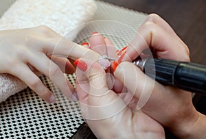 Nail technician saws and attaches a nail shape during the procedure of nail extensions with gel in the beauty salon. photo