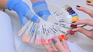 Nail technician shows the color palette of nail services in beauty salon