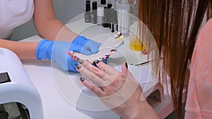 Nail technician shows the color palette of nail services in beauty salon