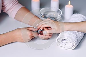 Nails beauty. Woman hands receiving nail care treatment by professional manicure specialist in nail salon. Manicurist