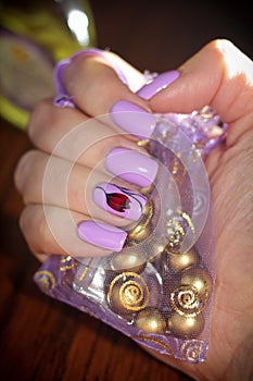 Nails lilac color on the background of the bag with the jewelry