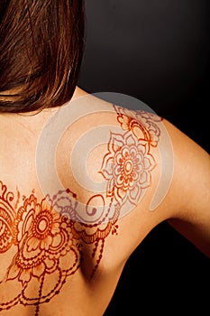 Naked back of young girl with henna tattoo mehendi
