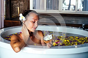 Naked brunette young woman relaxing in bath with petals in tropics. Time for yourself.romantic 14 february valentine day