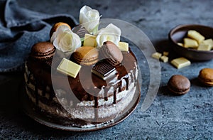 Naked cake filled with mascarpone cream, topped with chocolate and decorated with flowers, macarons and chocolate pieces