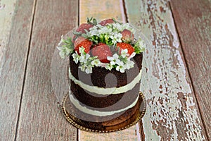 Naked chocolate cake, filled with coconut brigadeiro. Decorated with strawberries and white kalanchoe flowers on the table