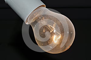 Naked dusty light bulb glows electricity