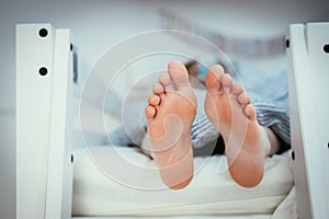 Naked feet of a young girl in bed, morning