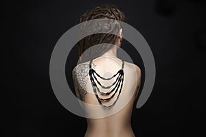 Naked Girl with tattoo and necklace on her back