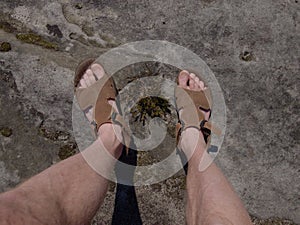 Naked hairy male legs with leather sandals rest while trail