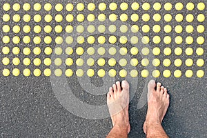 Naked human barefoot on asphalt road at tactile bumps pavin