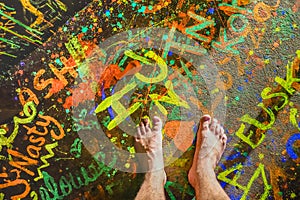 Naked human barefoot on fluo neon painted floor at beach party