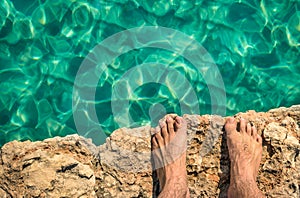 Naked human barefoot on rock cliff ready to jump