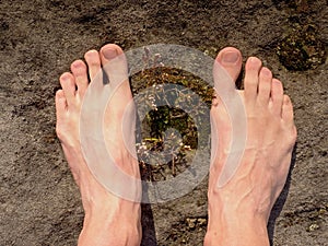 Naked male feet on dry sandstone. Fresh pink skin, shor tnails. Foot on pure nature ground