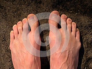 Naked male feet on dry sandstone. Fresh pink skin, shor tnails. Foot on pure nature ground