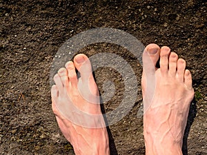 Naked male feet on dry sandstone. Fresh pink skin, shor tnails. Foot on pure nature ground