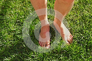 Naked male feet standing on the vivid green grass. Conceptual for foot health and therapy