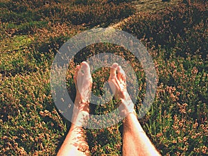 Naked male legs on peak make step. Sandstone rock above valley with tired hikers legs without shoes.