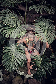 Naked male with painted face in jungle