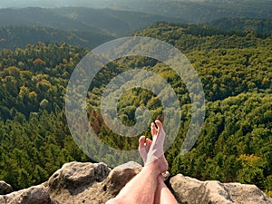 Naked male sweaty legs on peak of rock above valley. The end of trek