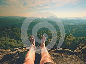 Naked male sweaty legs on peak of rock above valley. The end of trek