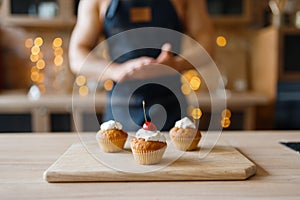 Naked man in apron cooking cakes with cherry