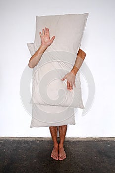 Naked man behind white pillow isolated over white background
