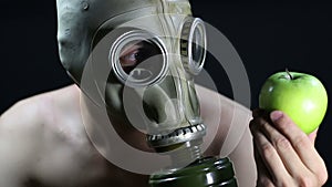 Naked man in a gas mask holding green Apple
