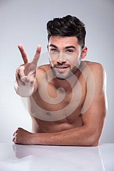 Naked man making the victory peace hand sign