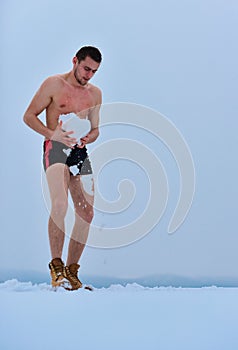 Naked man takes a snow shower. Healthy cold swim. Winter fun, tempering procedures. Guy snow showers for the hardening