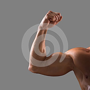 Naked muscular male hand showing pumped biceps. Close up shot. Male beauty concept.  on a gray background