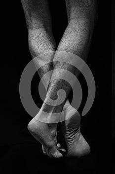 Naked muscular male legs on a black background