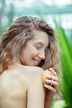 Naked smiling woman holding a bar of orange soap